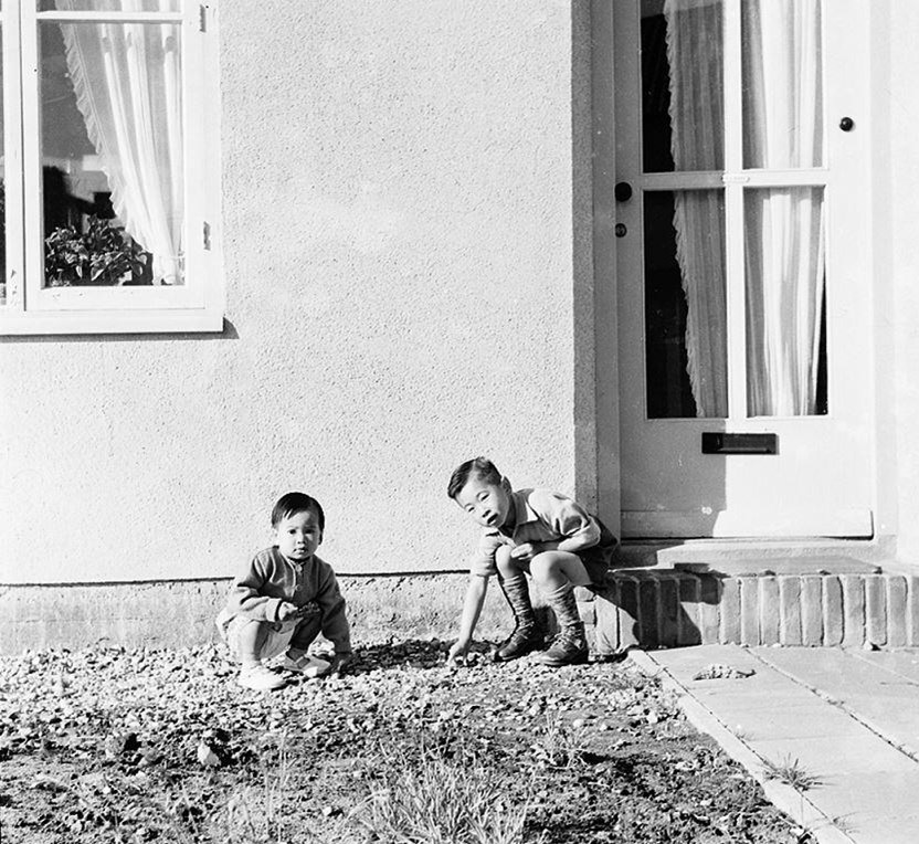 Broer en zus spelend voor het ouderlijk huis in de Hoolboomstraat in de 